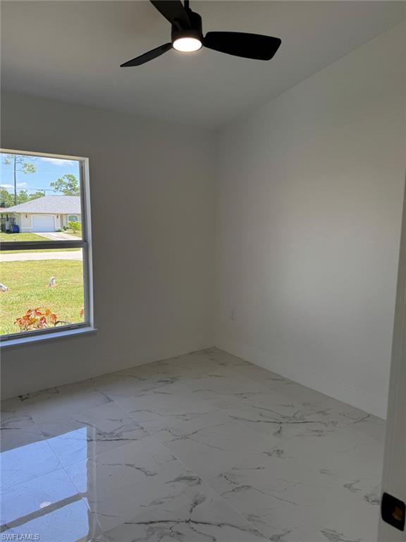 White walls with a black ceiling fan, large window, and patterned tile flooring