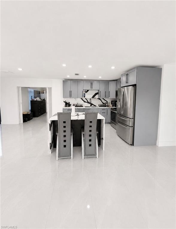Open-concept kitchen with light gray cabinetry, stainless steel appliances, and a central island