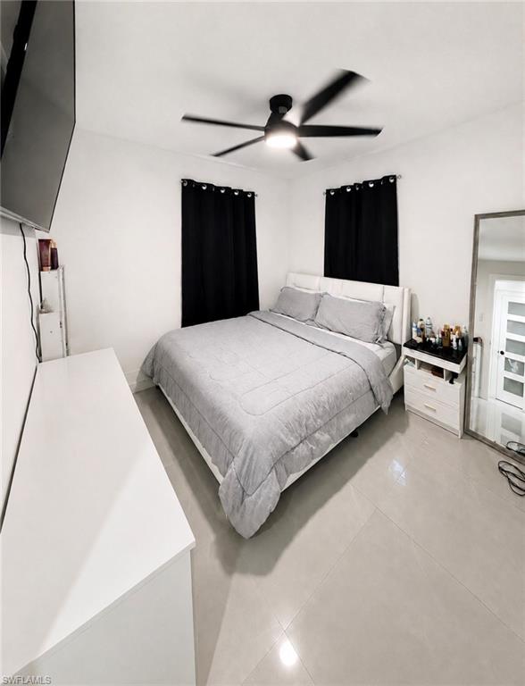 White walls, light-toned tile flooring, and a modern ceiling fan