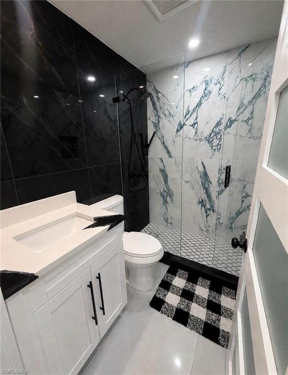White shaker vanity with black hardware, white rectangular sink, and black countertop