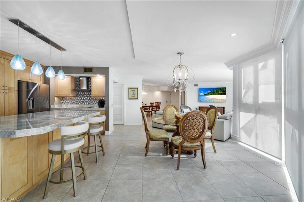 Tiled dining room featuring crown molding and a chandelier