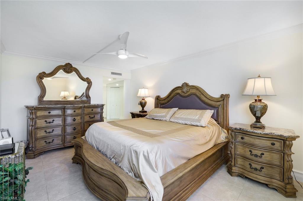 Bedroom with light tile patterned floors, ornamental molding, and ceiling fan