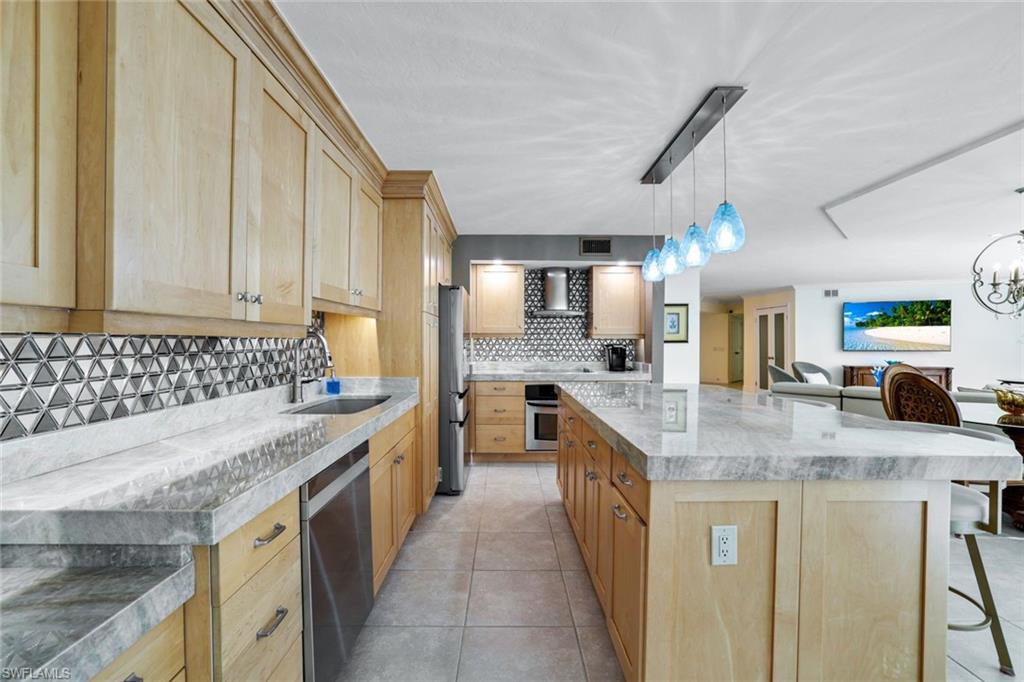 Kitchen featuring appliances with stainless steel finishes, wall chimney exhaust hood, sink, and light brown cabinets