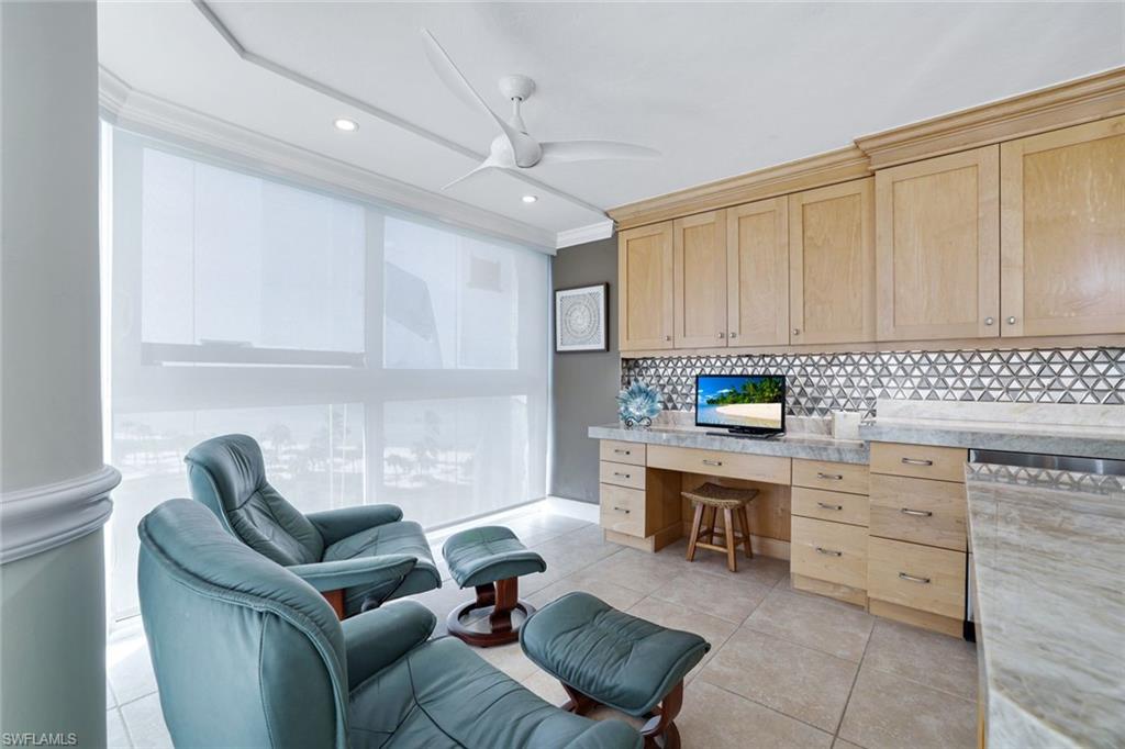 Office featuring built in desk, crown molding, light tile patterned flooring, and ceiling fan