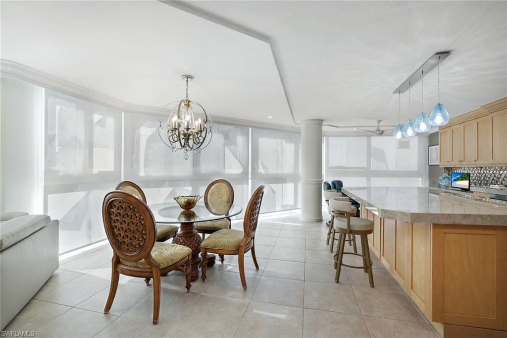 Tiled dining room with rail lighting, a chandelier, and ornate columns