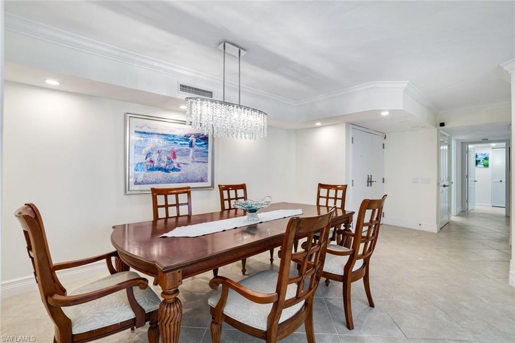 Tiled dining room with ornamental molding and an inviting chandelier