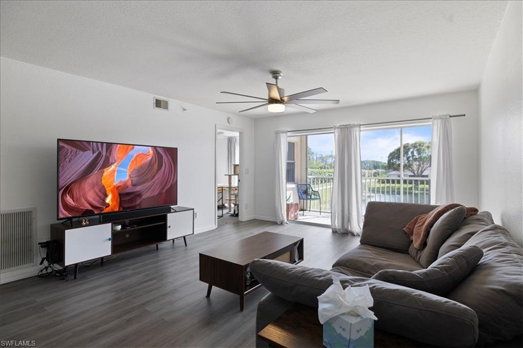 Spacious living area featuring wood-finish flooring, a ceiling fan with integrated lighting, and direct access to an outdoor balcony