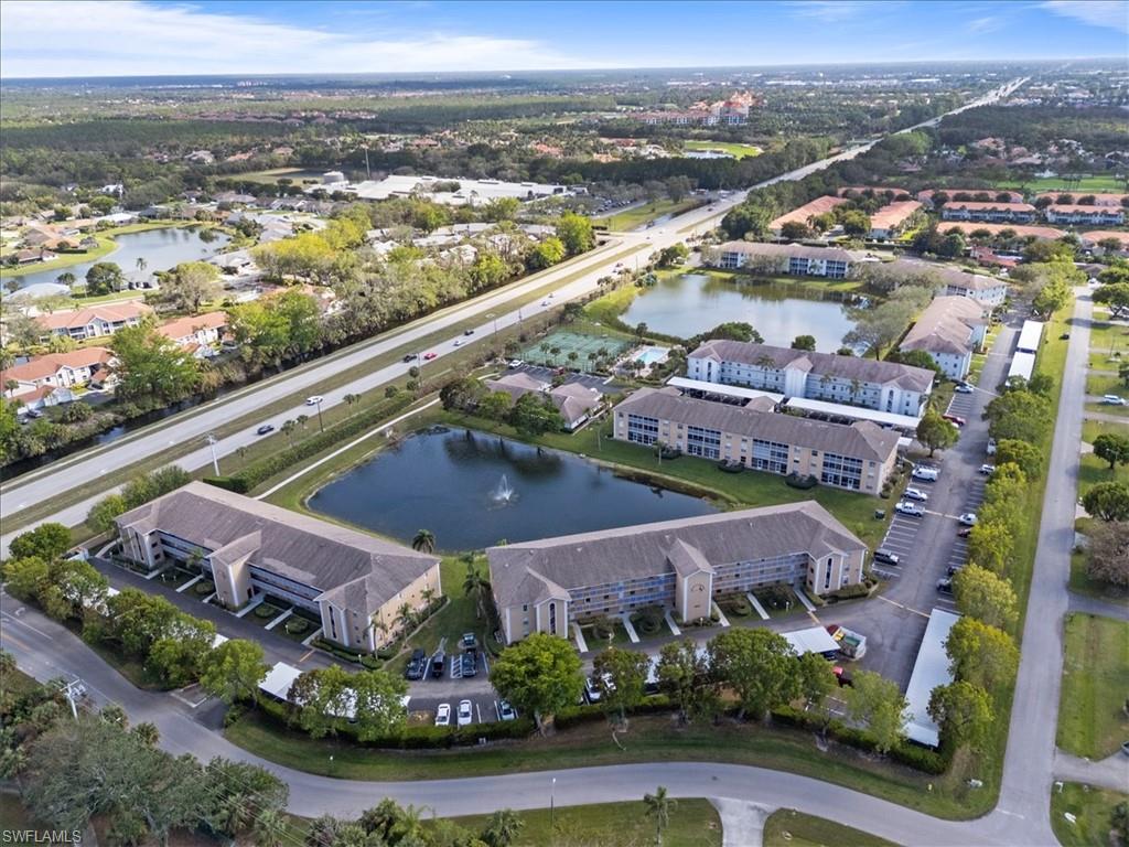 Aerial property overview featuring multiple apartment buildings, surrounding roadways, and central water features