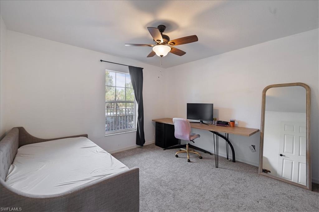 Recessed window with dark curtain rod and drapes, ceiling fan with light fixture, and neutral carpet flooring