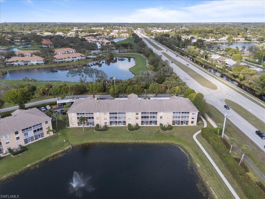 Three-story condominium building featuring private balconies, a water feature, and a paved pathway