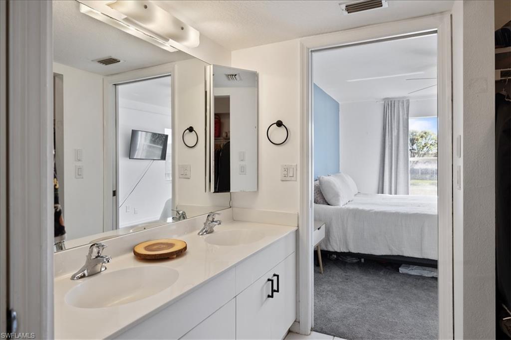 Double vanity with undermount sinks, chrome fixtures, and white cabinetry featuring black hardware