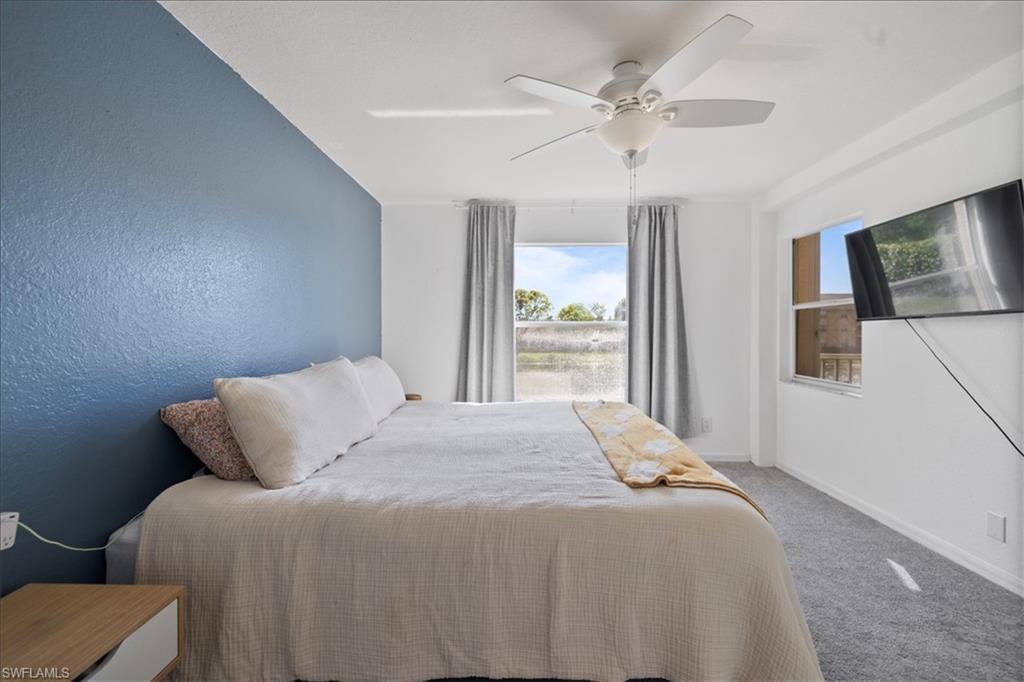 Accent wall, ceiling fan, window with natural light, wall-mounted television, carpeted flooring