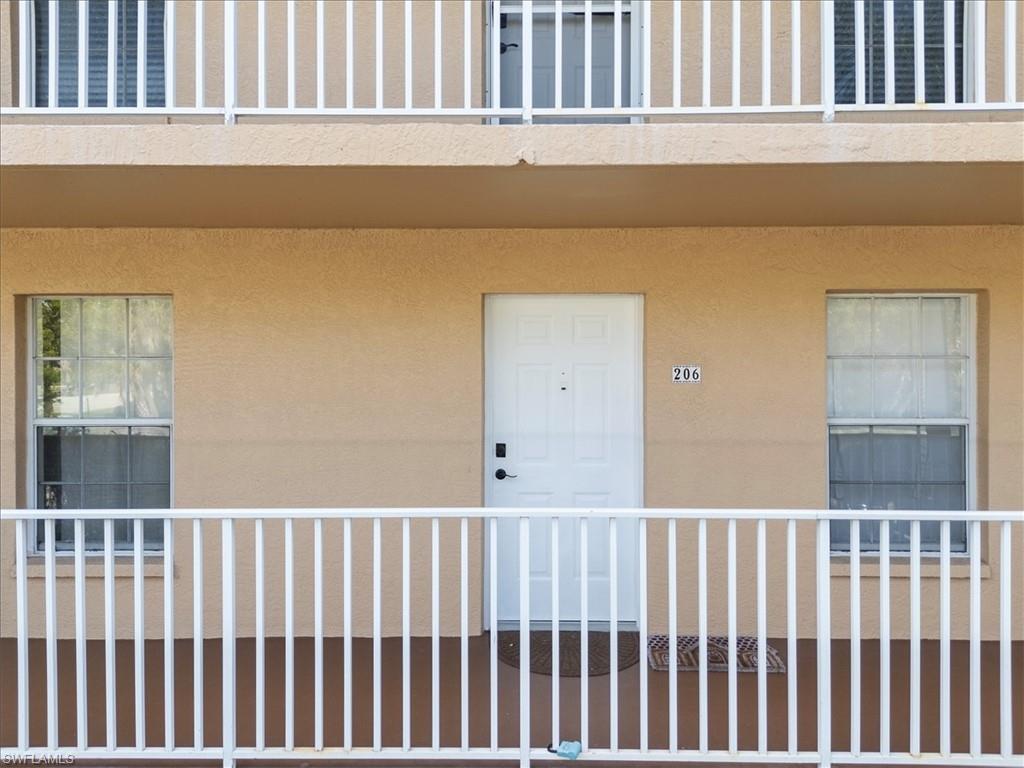 White balustrade balcony with a light brown stucco exterior and white entry door