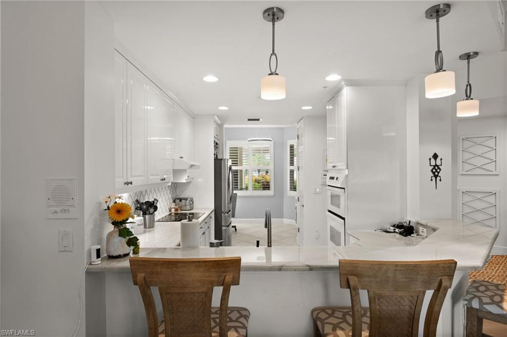 Kitchen featuring white cabinetry, light-toned countertops, recessed lighting, and pendant fixtures