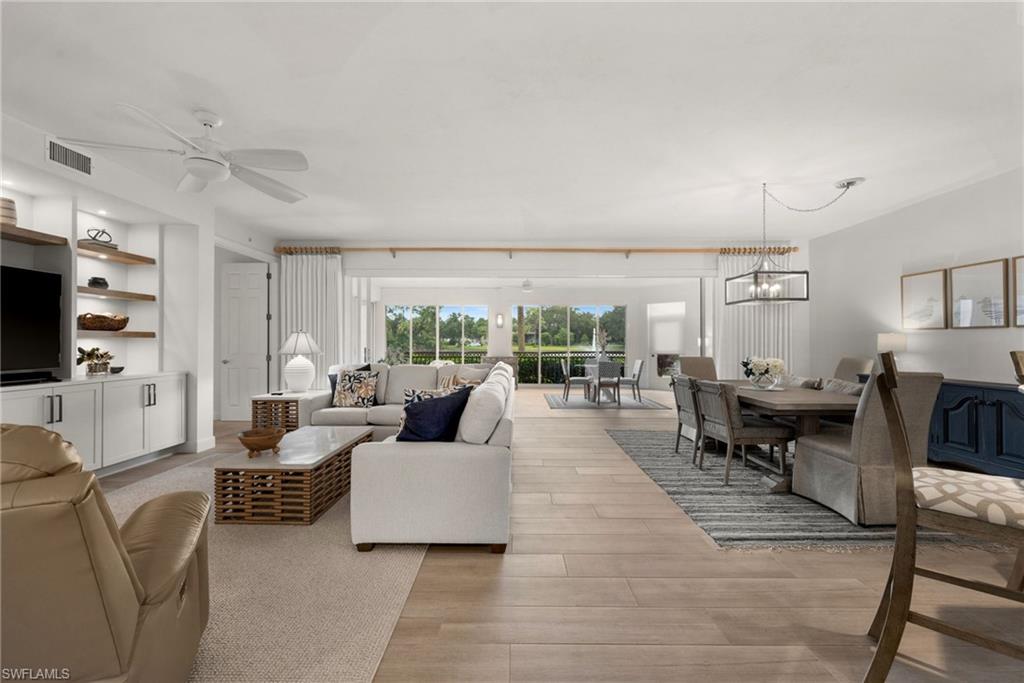 Spacious living area featuring wood-finish flooring, built-in shelving, and a dedicated dining space with a contemporary chandelier