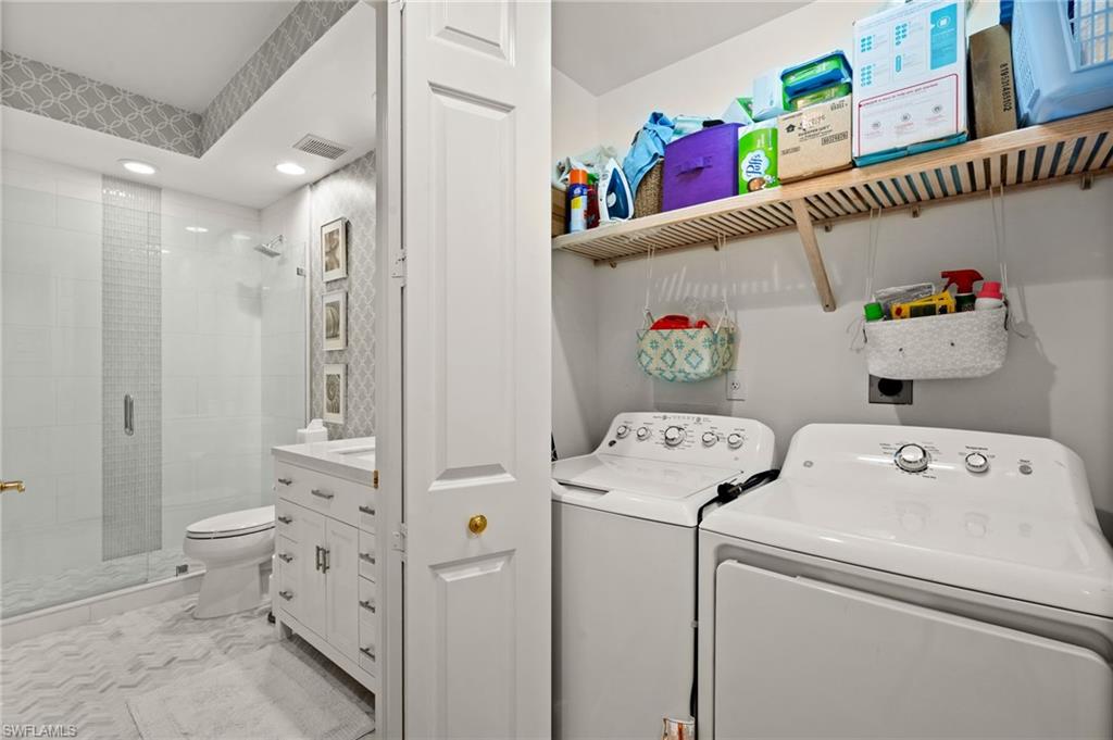 White top-load washer and dryer with a slatted wood storage shelf