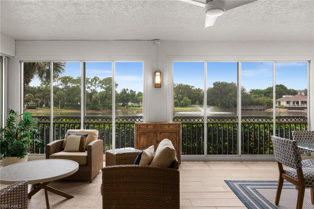 Expansive screened-in porch with wood-finish flooring, a ceiling fan, and multiple sliding glass doors opening to a water feature with a fountain