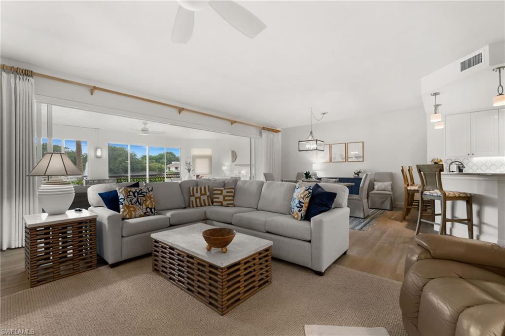 Expansive living area with wood-finish flooring, white walls, and a ceiling fan