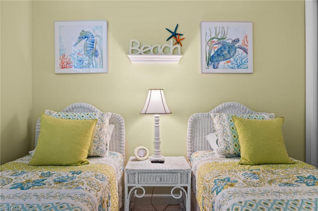 Two individual beds featuring wicker headboards, a central wicker nightstand, and a table lamp