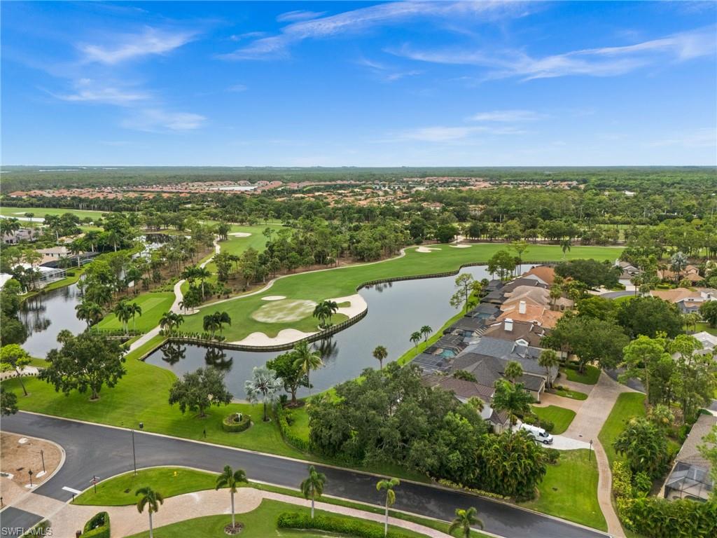 Expansive golf course and water features, lush green landscaping, mature trees, and residential properties with tiled roofs