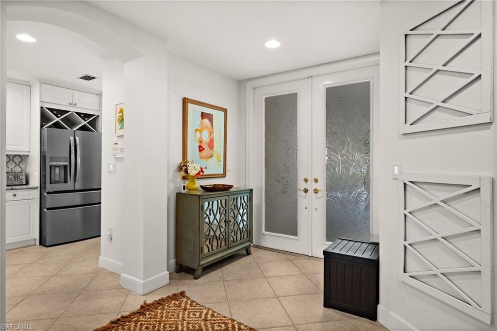 Tile flooring, double entry doors with frosted glass panels, recessed lighting, built-in wine storage, and a stainless steel French door refrigerator