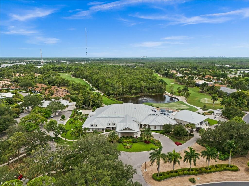 Extensive golf course, water feature, paved parking areas, abundant mature trees, and a large building with multiple gables