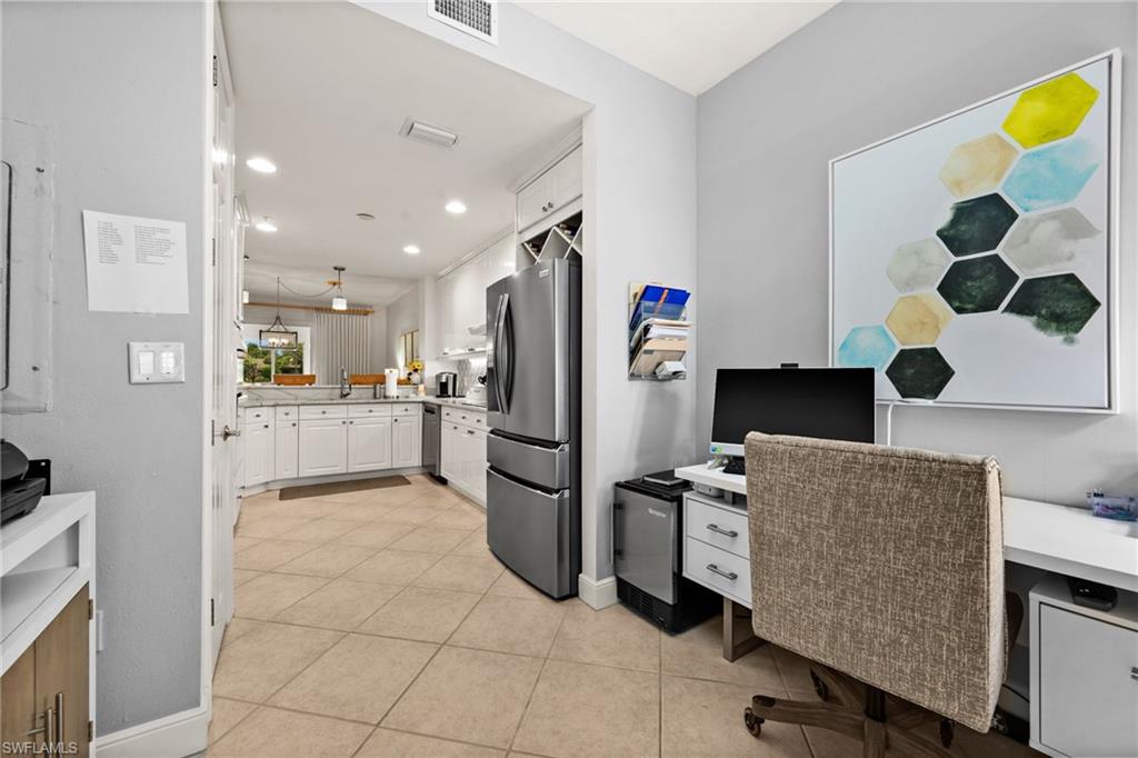 Kitchen with stainless steel refrigerator, white cabinetry, and recessed lighting