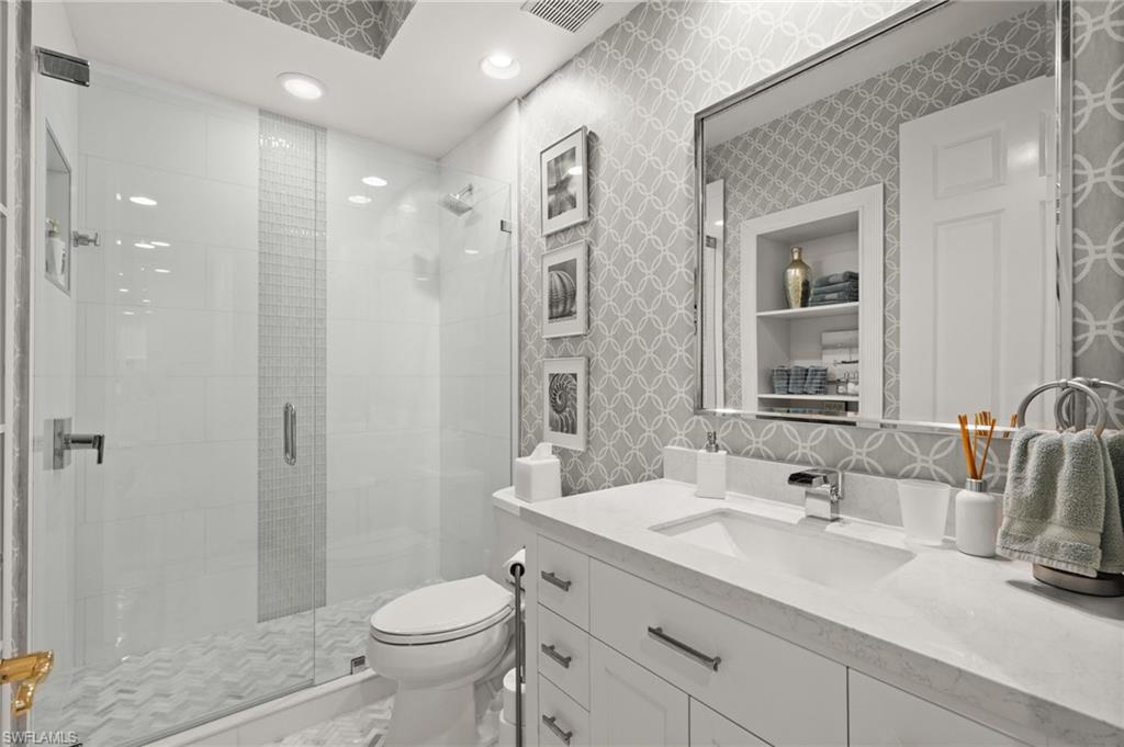Glass-enclosed shower with a chevron-patterned floor and vertical tile accent