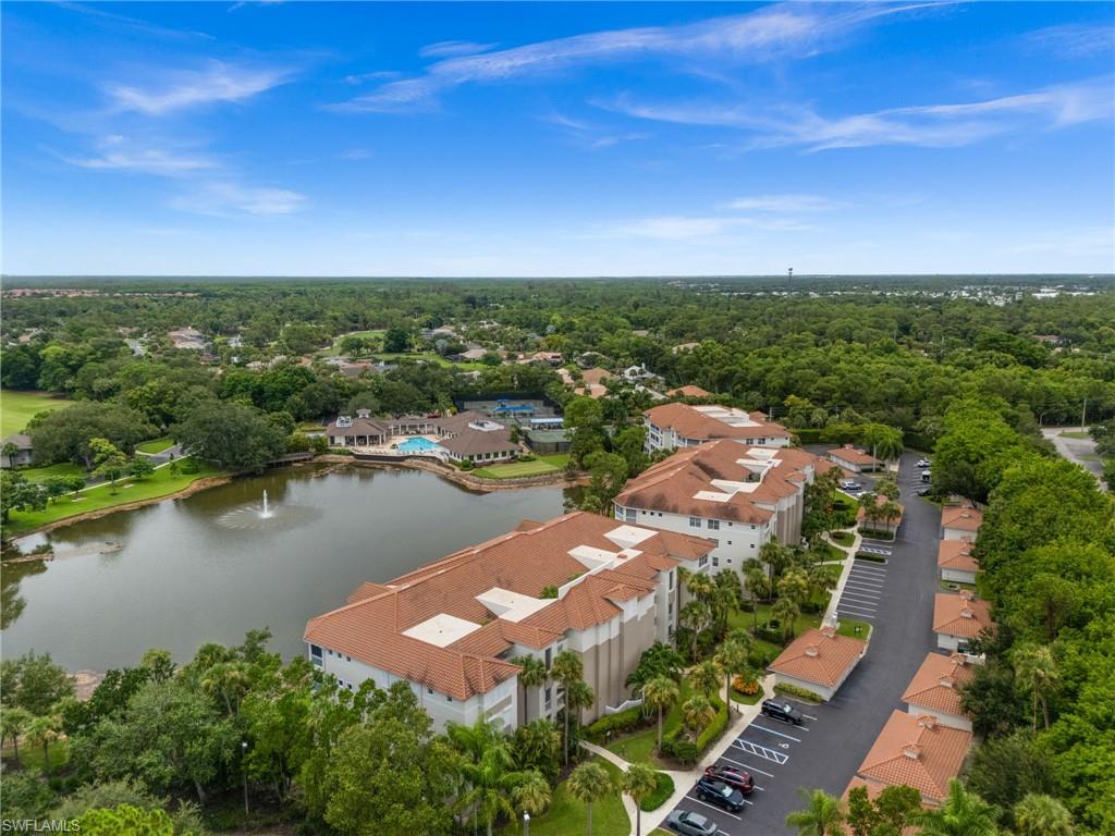 Lakeside community with multiple residential buildings, paved parking areas, and abundant mature trees