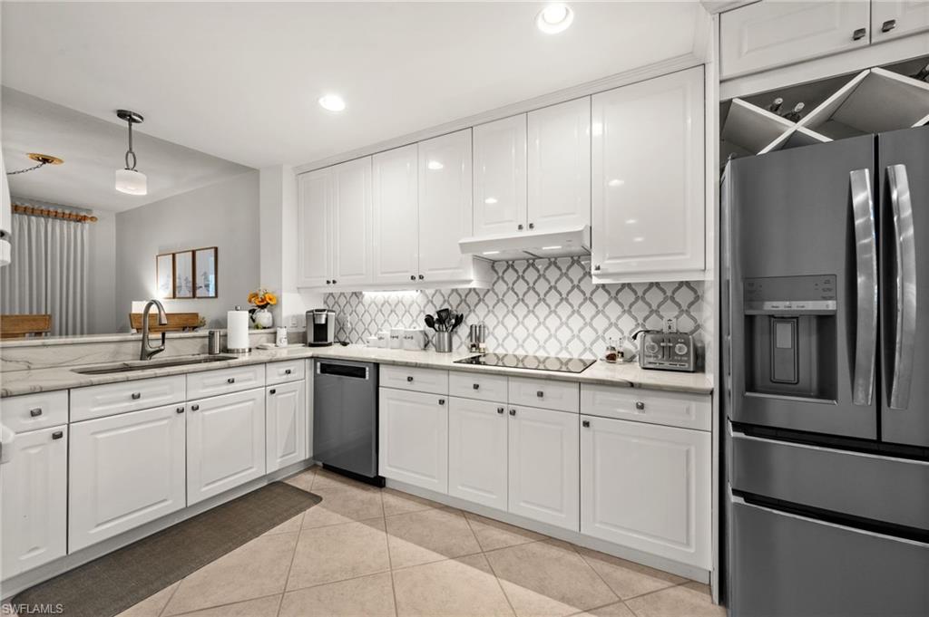 White cabinetry with dark hardware, stone countertops, and a patterned tile backsplash