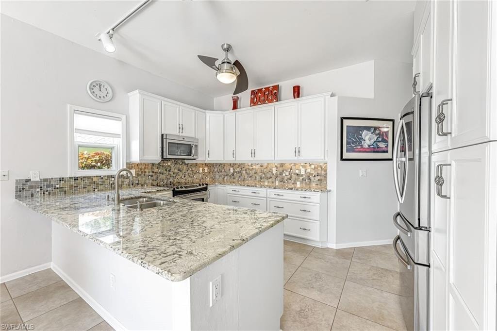Kitchen has undercounter lighting, decorative backsplash, ceiling fan and pennant lighting.