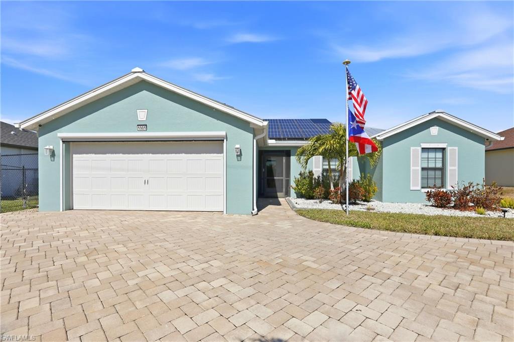Paver driveway leading to a two-car garage with a roll-down hurricane shutter