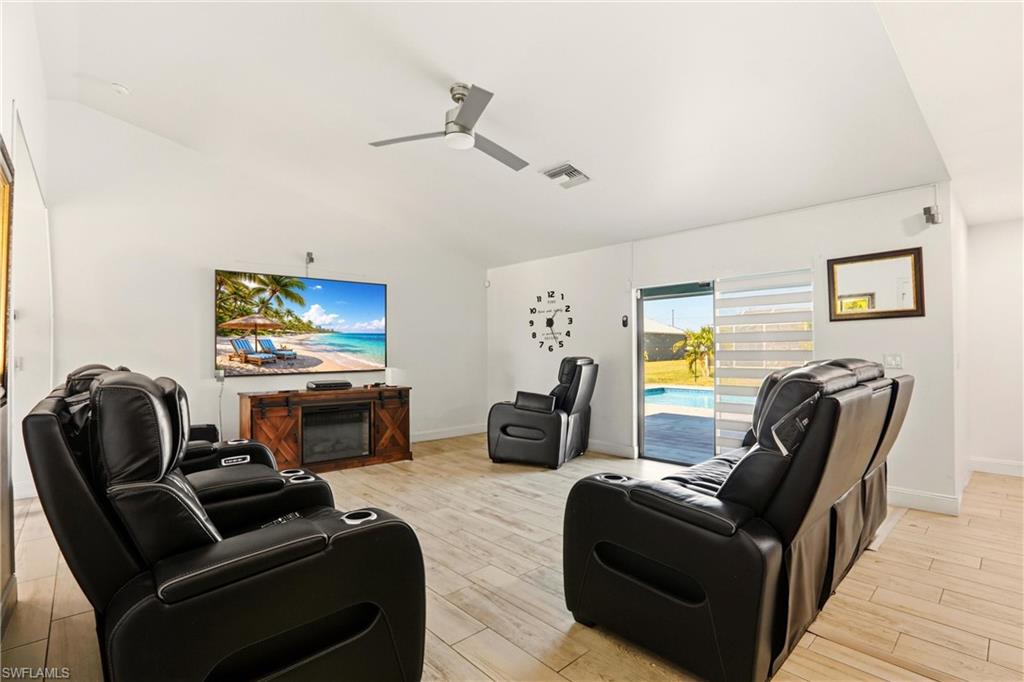 Vaulted ceilings with a ceiling fan, light wood-finish flooring, sliding glass door, and a visible pool