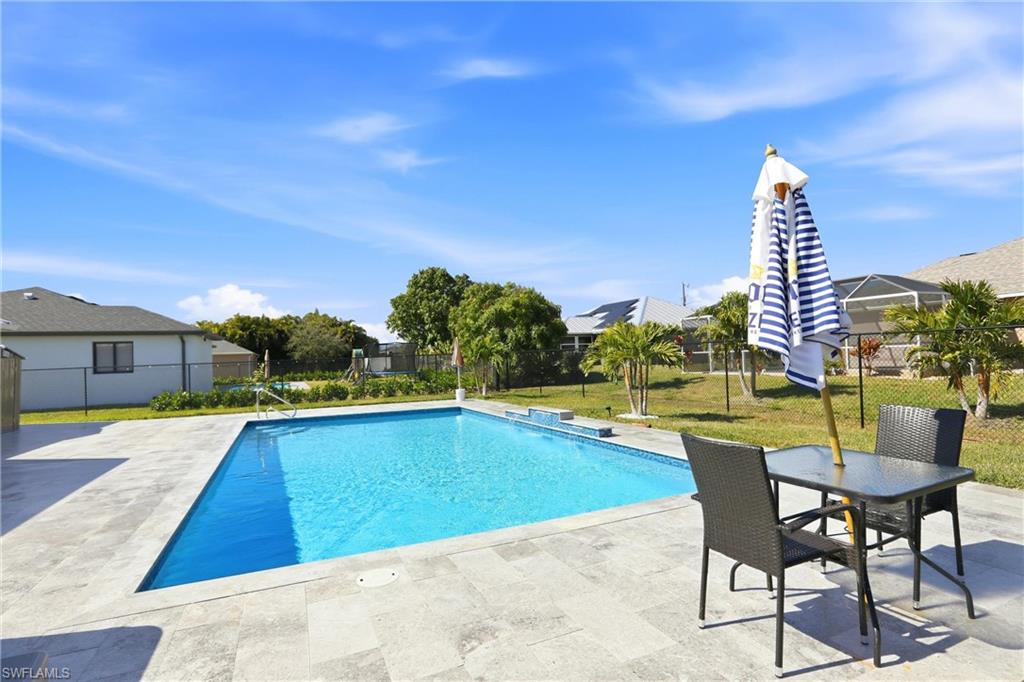 Expansive backyard featuring a rectangular swimming pool, concrete pool deck, and mature landscaping