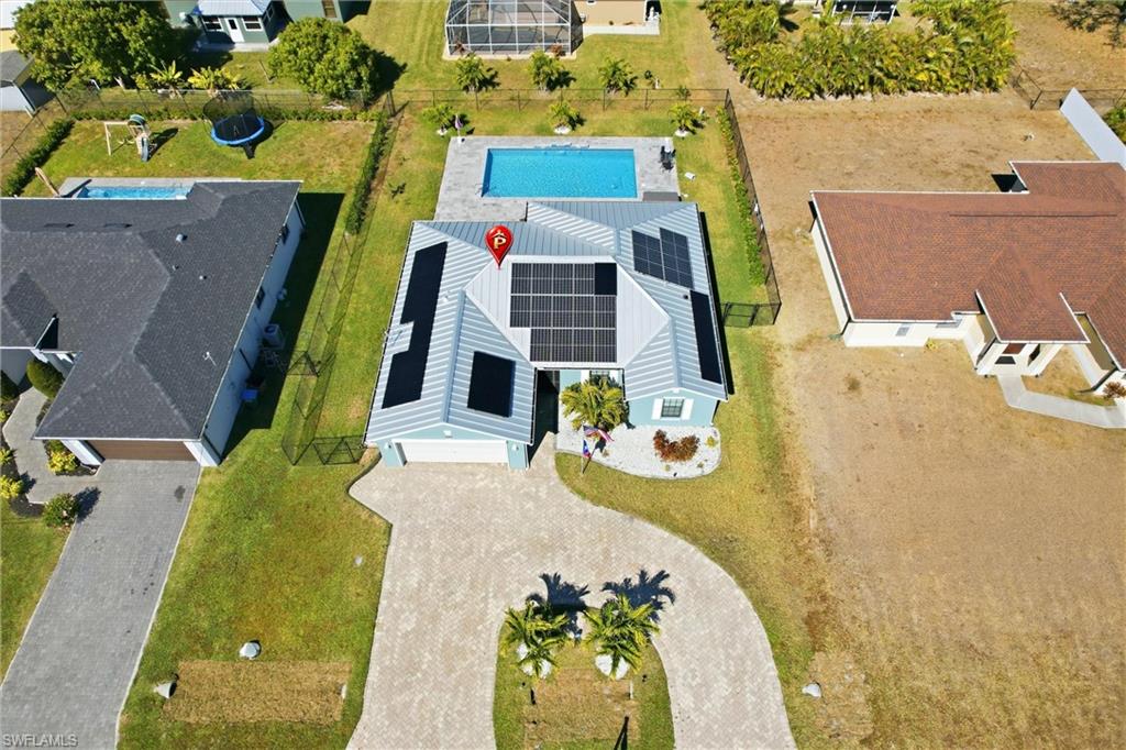 Exterior featuring a private pool, an expansive paved driveway, multiple solar panels, and mature landscaping