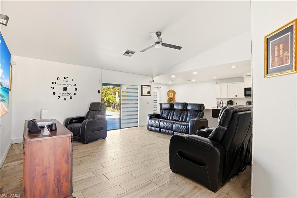 Vaulted ceiling, wood-finish flooring, recessed lighting, ceiling fan, and sliding glass doors