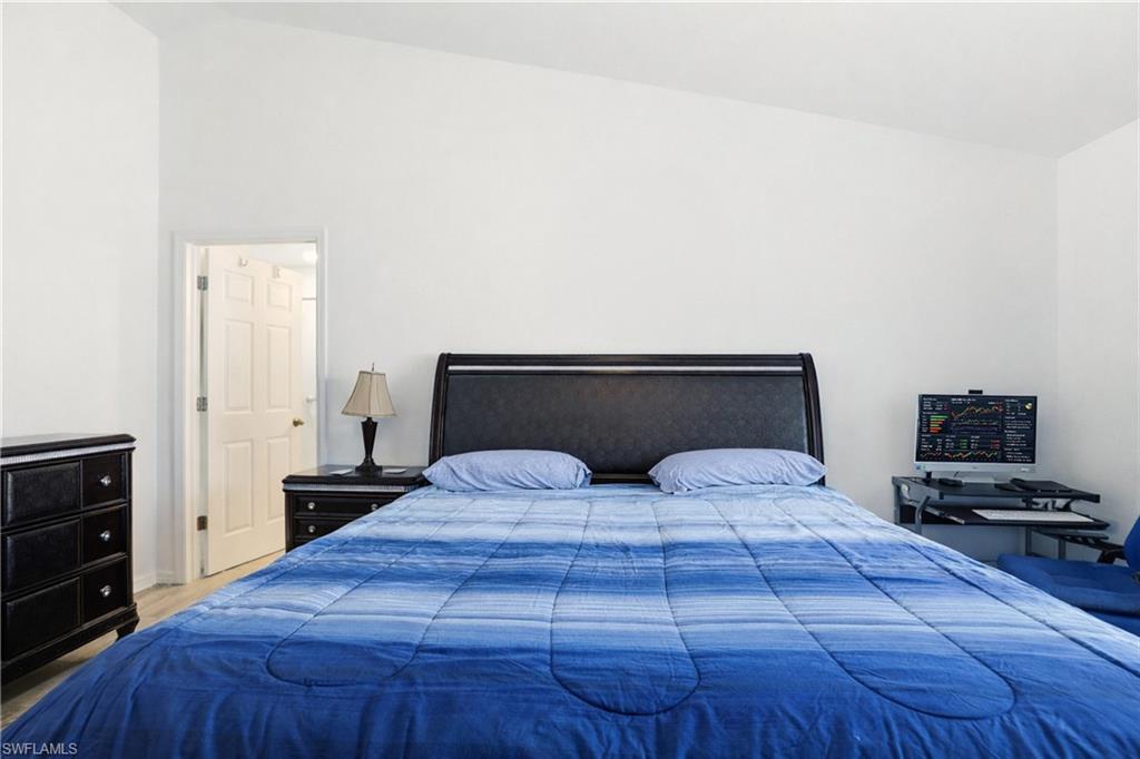 Vaulted ceiling, light-toned flooring, white walls, and a white door with dark hardware