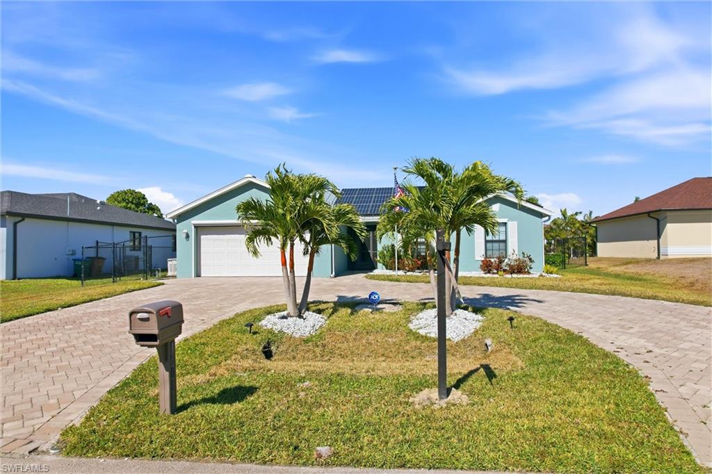 Stucco exterior residence featuring a paver driveway, an attached garage, and landscaping with palm trees