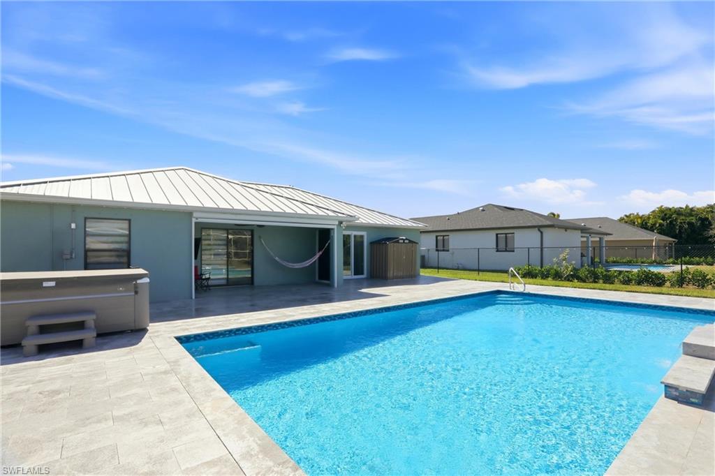Expansive backyard featuring a large swimming pool, patio with light-toned pavers, and a covered lanai