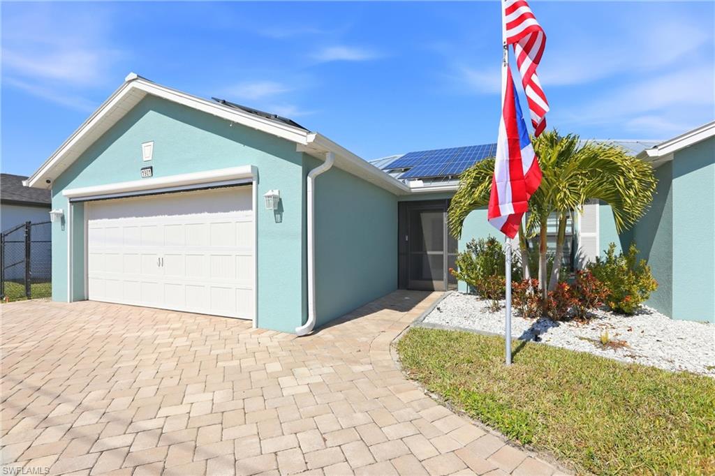 Light blue exterior with white trim, a paved driveway, and solar panels