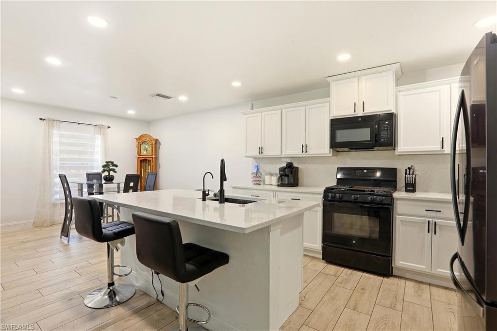 Modern kitchen featuring white cabinetry, light-toned countertops, and a central island with a built-in sink
