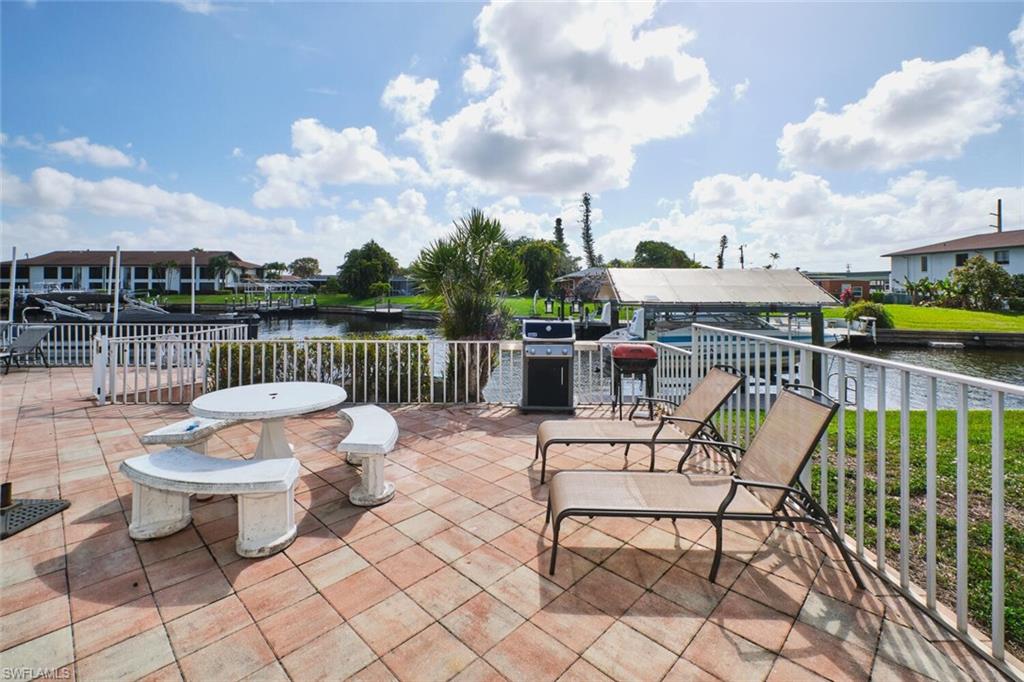 Tiled patio area with a white railing, overlooking a canal with boats