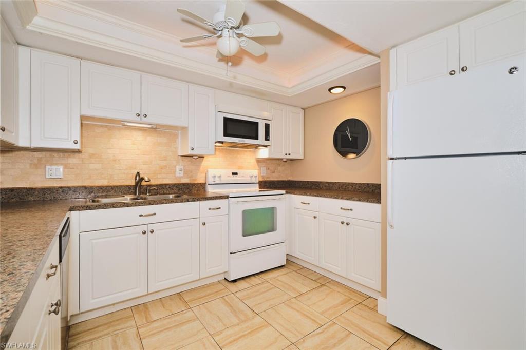 Kitchen featuring white cabinetry, a tiled backsplash, granite-style countertops, integrated appliances, and tiled flooring