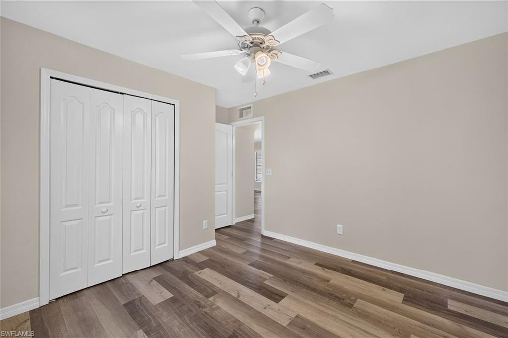 Wood-finish flooring, neutral wall tones, white bi-fold closet doors, and a ceiling fan with integrated lighting