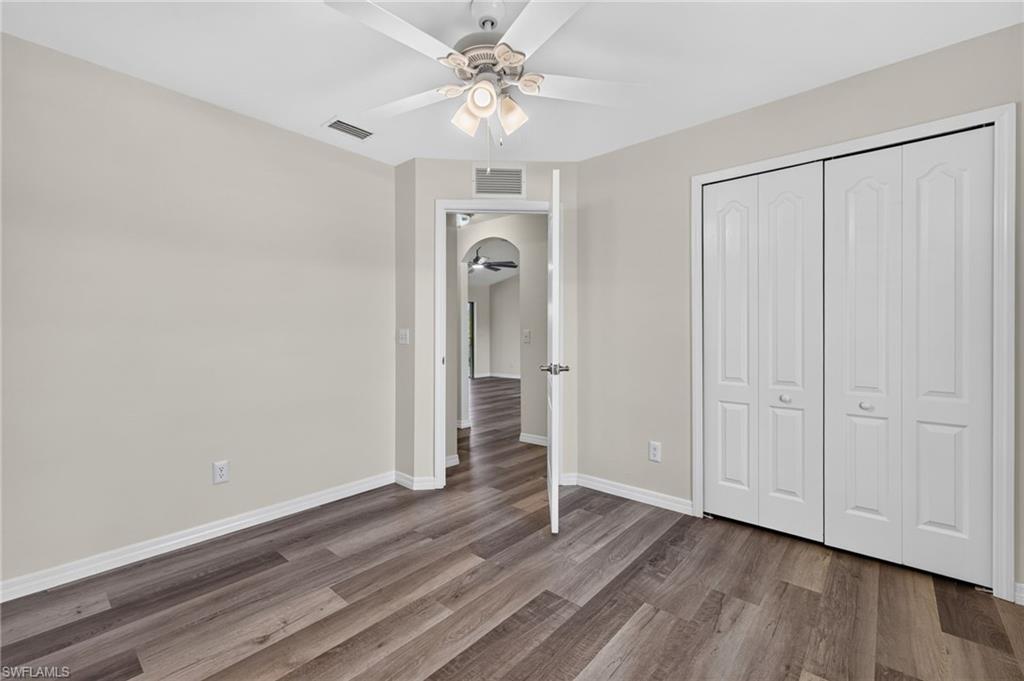 Wood-finish flooring, ceiling fan with light kit, bi-fold closet doors, and neutral wall tones