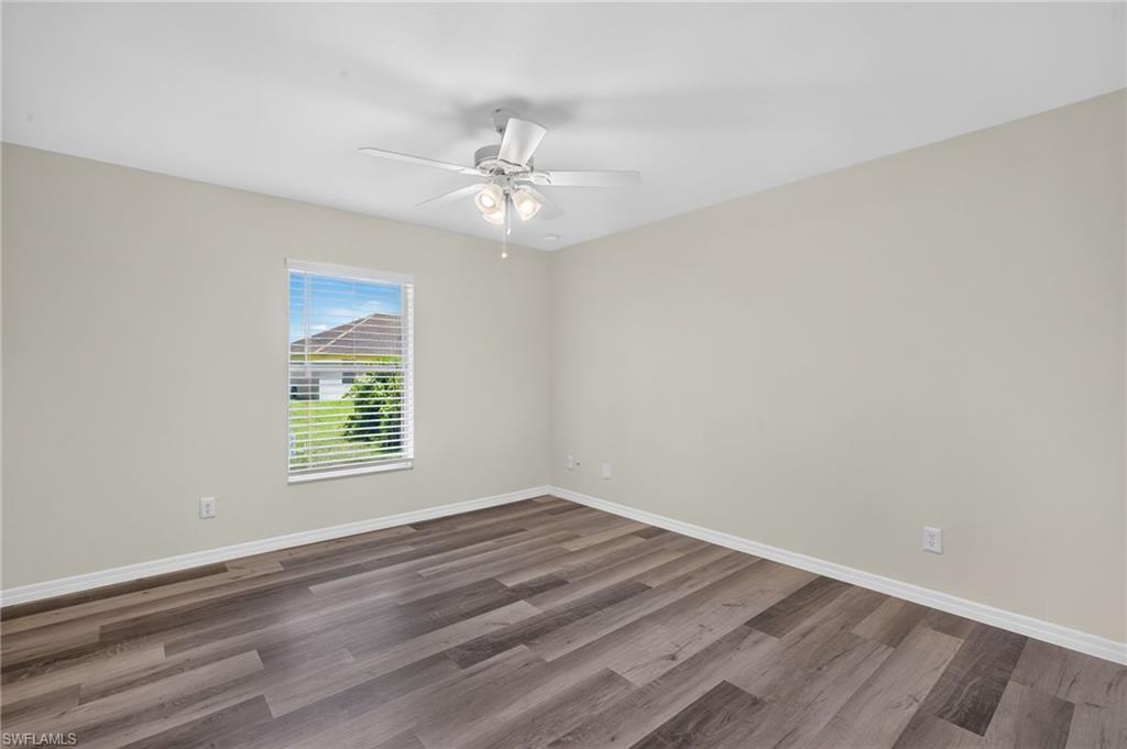 Wood-finish flooring, white ceiling fan with integrated lighting, window with horizontal blinds, and neutral painted walls