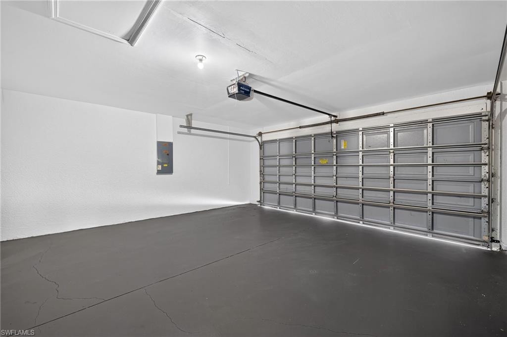 Spacious garage featuring a grey sectional garage door, painted concrete flooring, and ceiling-mounted lighting