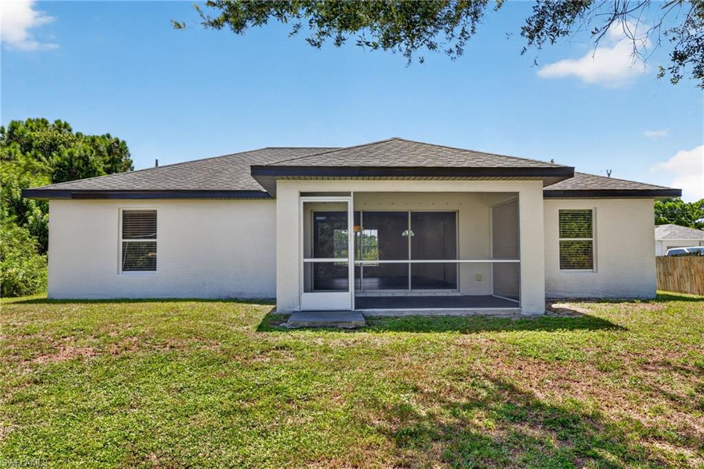 Stucco exterior with a screened-in patio, sliding glass doors, and a dark shingle roof