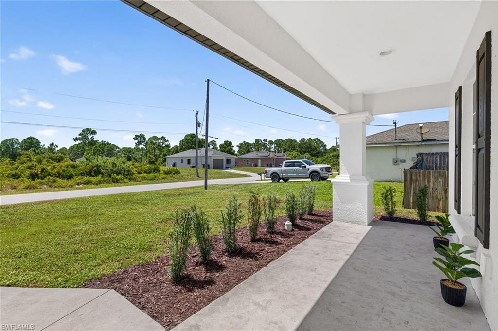 Covered entry with a concrete walkway, decorative column, and dark window shutters