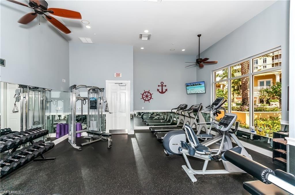Exercise room with ceiling fan, a high ceiling, and recessed lighting